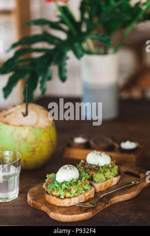 Délicieux petit-déjeuner biologique sain - avocat sur des toasts avec des oeufs pochés, des jeunes noix de coco Banque D'Images