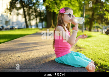 Cute little girl sur l'eau potable chaude journée d'été. Enfant tenant une bouteille de l'eau. Banque D'Images