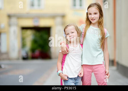Deux mignonnes petites sœurs ayant une marche ensemble dans une ville de jour d'été chaud et ensoleillé Banque D'Images