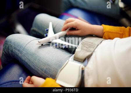 Adorable petite filles voyageant par avion. Des enfants assis par avion fenêtre et Playing with toy avion. Voyageant à l'étranger avec des enfants. Banque D'Images