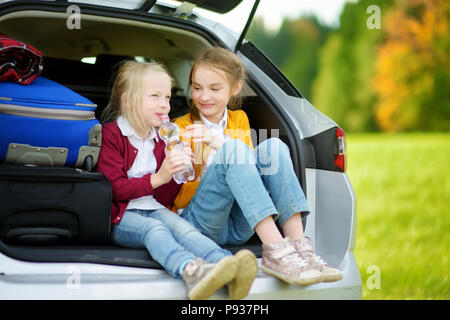 Deux adorables petites filles assise dans une voiture avant de partir en vacances avec leurs parents. Deux enfants à l'avant pour un voyage en voiture ou en voyage. Famille tr Banque D'Images