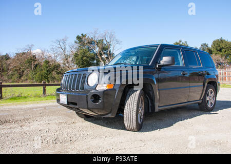 Jeep Patriot noir véhicule utilitaire sport (VUS) dans l'air extérieur avec fond naturel de la Californie - vue latérale de la plaque d'immatriculation Banque D'Images
