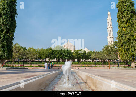 Les visiteurs de la Grande Mosquée Sultan Qaboos à Mascate, Oman marche à travers les jardins en direction de la grande salle de prière Banque D'Images