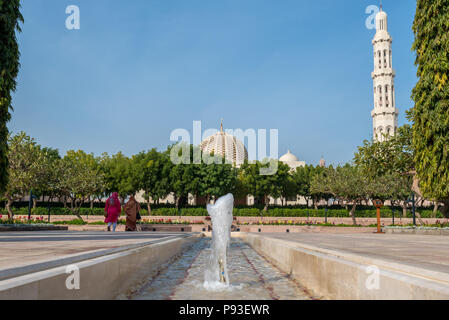 Les visiteurs de la Grande Mosquée Sultan Qaboos à Mascate, Oman marche à travers les jardins en direction de la grande salle de prière Banque D'Images