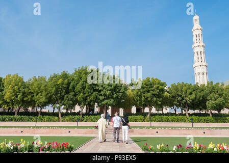 Les visiteurs de la Grande Mosquée Sultan Qaboos à Mascate, Oman marche à travers les jardins en direction de la grande salle de prière Banque D'Images
