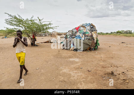 Kakuma, Kenya - sur le bord du camp de réfugiés Kakuma. Un jeune homme est au téléphone avec son mobile. Banque D'Images