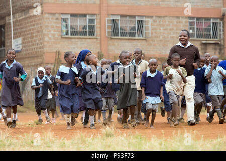 Nairobi, Kenya - Les étudiants en uniforme à pied avec un enseignant dans la cour de l'école de St John's Community Centre Pumwani. Banque D'Images