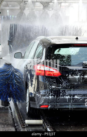 Passe en voiture lavage de voiture avec beaucoup de mousse, bleu en rotation des brosses et les feux arrière sont allumés Banque D'Images