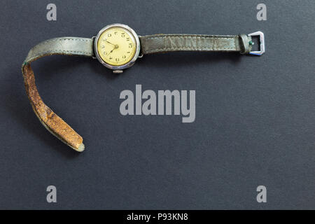 Libre de style rétro montre-bracelet de couleur jaune avec des lanières de cuir usé sur fond noir. Banque D'Images