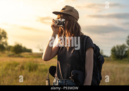 Jeune femme prenant touristique photo randonnée. Femme avec sac à dos est au coucher du soleil et des photographies belles Région rurale Banque D'Images