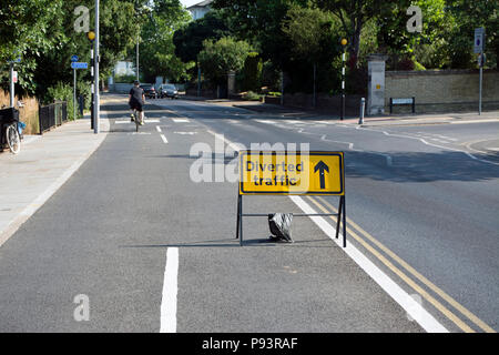 Le trafic détourné tout droit signe dans un segregarted voie cyclable, avec cycliste à moyenne distance, à Kingston upon Thames, Surrey, Angleterre Banque D'Images