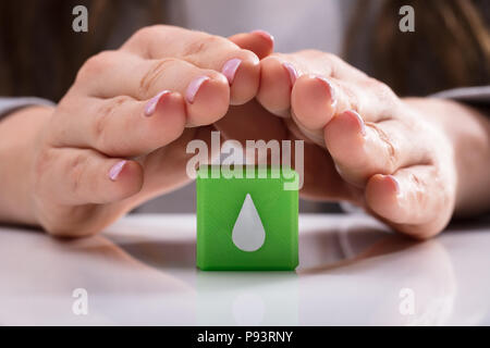 Woman's hand protection bloc cubes verts avec de l'eau goutte icône sur bureau Banque D'Images