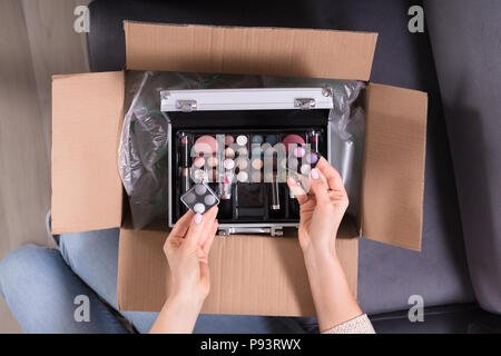 High Angle View Of A Woman's Hand Holding Produits cosmétiques de boîte en carton Banque D'Images