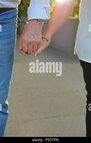 Vieux COUPLE HOLDING HANDS IN SUNSET CLOSE UP Banque D'Images