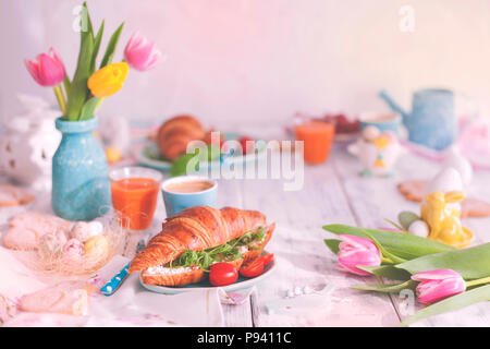 Vintage photo. Un petit déjeuner en famille de croissants de roquette et de fromage et de café aromatique, des œufs de couleurs différentes. Bouquet de tulipes Banque D'Images