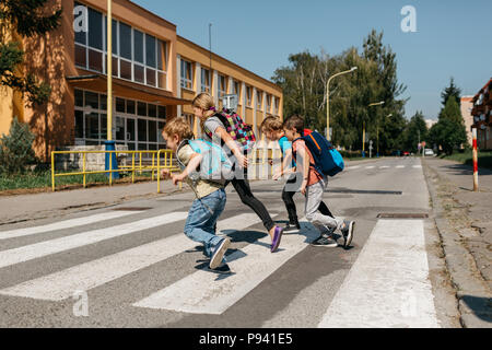 Les enfants de l'école à travers une rue à un passage pour piétons. Groupe d'élèves du primaire se précipiter à l'école. Banque D'Images