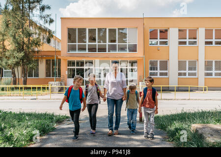 Enfants allant à la maison de l'école et de parler à leur mère. Les jeunes étudiants à s'éloigner de l'école, accompagnés par un parent. Banque D'Images