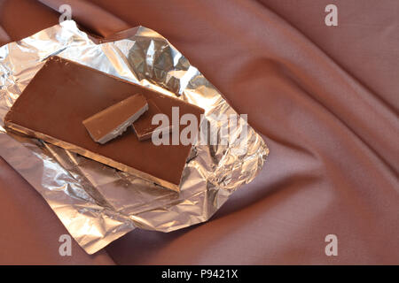 Barre de chocolat à ouvrir le couvercle isolé sur fond de nice avec tissu marron Banque D'Images