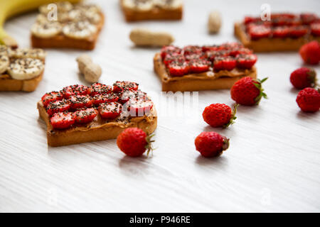 Toasts végétarien avec du beurre d'arachides, fruits et chia seeds on a white background, low angle. Concept de l'alimentation santé. Libre. Banque D'Images