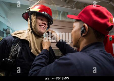 180710-N-GR120-0142 MER DES PHILIPPINES (10 juillet 2018) Yeoman 1re classe Michael Boyd, droite, un membre de l'équipe de la formation de contrôle des dommages, spécialiste de la logistique permet d'Apprenti matelot Kenneth Nemec lors d'un forage à bord de l'quarts de la classe Arleigh Burke destroyer lance-missiles USS Benfold (DDG 65). Benfold est l'avant-déployés dans la 7e flotte américaine zone d'opérations à l'appui de la sécurité et de la stabilité dans la région Indo-Pacifique. (U.S. Photo par marine Spécialiste de la communication de masse 2e classe Anna Van Nuys/libérés) Banque D'Images