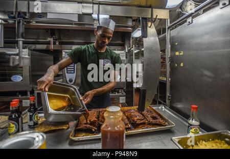 180710-N-PJ626-0127 MER DES PHILIPPINES (10 juillet 2018) Spécialiste culinaire Seaman Apprentice Dylan Duplessis, de Chicago, se prépare dans une côtelette de cuisine carré des officiers de la marine à bord de l'avant-déployé porte-avions USS Ronald Reagan (CVN 76). Ronald Reagan, le groupe aéronaval du porte-étendard de 5, fournit une force prête au combat qui protège et défend les intérêts de maritime collective de ses alliés et partenaires dans la région Indo-Pacifique. (U.S. Photo par marine Spécialiste de la communication de masse 2e classe Kaila Victoria Peters/libérés) Banque D'Images