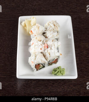 Rouleaux de sushi avec du saumon et la chair de crabe sur une plaque sur une table en bois. Vue de côté. Banque D'Images