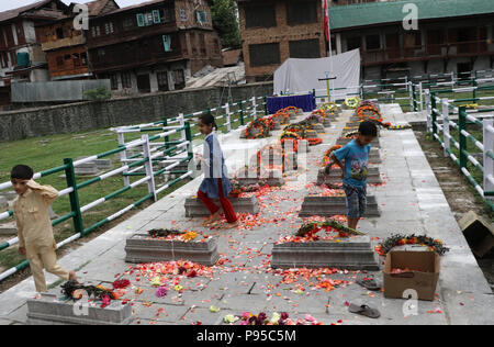 L'Inde. Le 13 juillet, 2018. Les enfants jouent dans le cimetière des Martyrs lt à Srinagar, au Cachemire sous contrôle indien, vendredi 13 juillet, 2018. Le 13 juillet est célébrée comme Journée des martyrs en mémoire de la journée lorsque le roi hindou de la région a commandé plus de 20 musulmans du Cachemire exécuté dans une soumission pour mater une insurrection en 1931. Chaque année, le gouvernement local dans la région observe l'occasion de se souvenir de ces martyrs en visitant leur cimetière et portant des couronnes de fleurs : Crédit Umer Asif/Pacific Press/Alamy Live News Banque D'Images