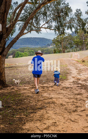 Petit garçon marchant à travers la campagne australienne avec son grand-père. Banque D'Images