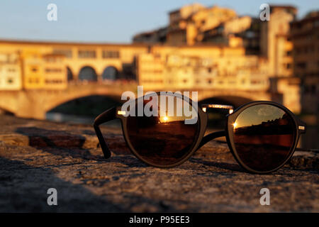 Le soleil couchant se reflétant dans une paire de lunettes de soleil avec le célèbre Ponte Vecchio de Florence, en Italie, dans l'arrière-plan Banque D'Images