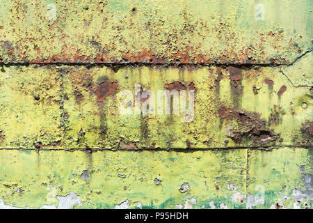 L'écaillage de la peinture verte qui contraste avec l'orange rouille sur une porte métallique Banque D'Images