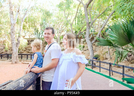 Happy Family - parents avec bébé fille enfant s'amusant dans le zoo. Loisirs en famille, passer du temps ensemble. Focus sélectif. Copy space Banque D'Images