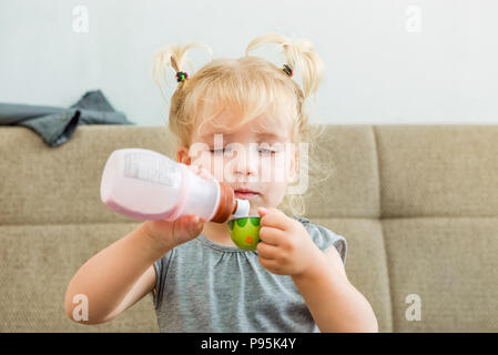 Close up cute girl pouring yaourt naturel à partir de bouteille en plastique à toy tasse à la maison . Saine alimentation, les habitudes alimentaires. L'enfant du soutien, de l'éducation c Banque D'Images