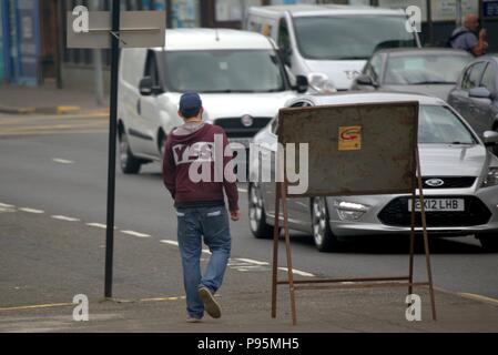 Gritty urban street shot of male blanc garçon adolescent avec oui t shirt sweat shirt capuche vu de derrière Banque D'Images