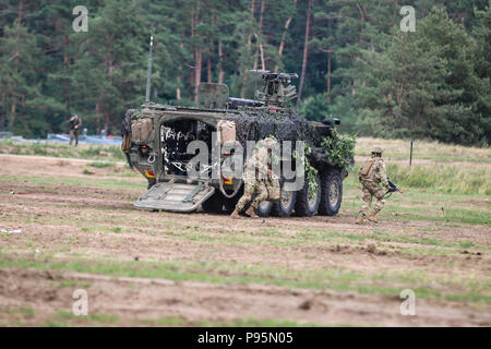 Les soldats de l'armée américaine avec 1er Escadron, 2e régiment de cavalerie quitter un véhicule blindé intérimaire 'Stryker" au cours de la 15e Brigade mécanisée du réservoir d'une célébration de la Bataille de Pologne Groupe Orzysz, Pologne le 14 juillet 2018. La Pologne est un groupe de combat, unique coalition multinationale d'États-Unis, Royaume-Uni, croate et soldats roumains qui servent avec la 15e Brigade mécanisée polonaise comme une force de dissuasion de l'OTAN à l'appui de l'amélioration de l'avant la Présence. (U.S. Photo de l'armée par la CPS. Hubert D. Delany III /22e Détachement des affaires publiques mobiles) Banque D'Images