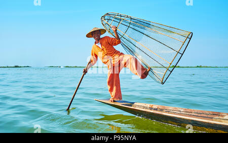 Lac Inle, MYANMAR - février 18, 2018 : pêcheur birman traditionnel pose tout en se tenant sur une jambe et maintenant le filet dans son kayak sur Inle Banque D'Images