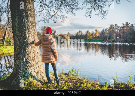 Girl in a red hat portant des écouteurs jouit de la vue d'un parc d'automne Banque D'Images