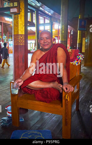 YWAMA, MYANMAR - février 18, 2018 : le portrait de moine bhikkhu souriant, assis sur une chaise avec mug de limonade au monastère Nga Phe Chaung, sur Februa Banque D'Images