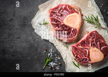 Steak de boeuf cru osso bucco sur noir table de pierre. En viande. Vue de dessus de près. Banque D'Images