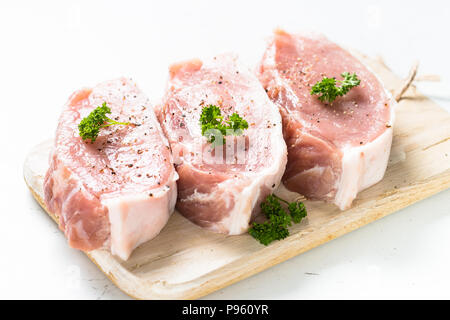 La viande de porc steak, tranches de porc sur une planche à découper sur blanc. Isolées. Banque D'Images