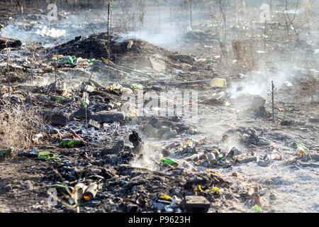 La combustion des déchets à la décharge illégale de déchets près de la forêt. Terre noire et lourde fumée indésirable. Conséquences de la pollution de l'environnement concept. Banque D'Images