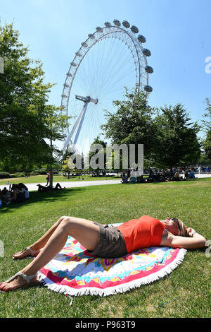 Ruth (nom retenu) relaxe au soleil sur l'herbe près du London Eye, sur la rive sud de Londres. Banque D'Images