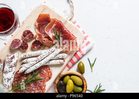 Antipasti italiens traditionnels, viandes tranchées ensemble avec le vin et les olives sur la table blanche. Vue de dessus, copiez l'espace. Banque D'Images