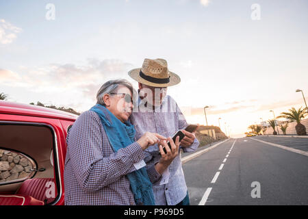 Joli couple en vacances à l'aide d'ensemble pour vérifier les smartphones road trip map ou appelez et connectez-vous au web. Belle belles personnes âgées de wit Banque D'Images