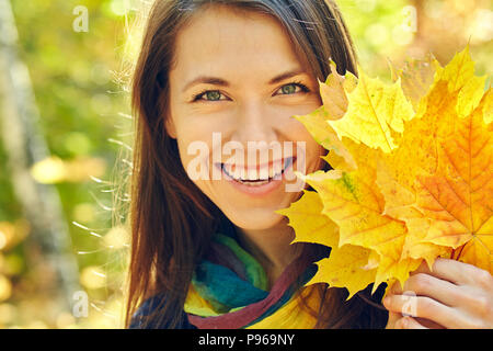 Femme avec des feuilles d'érable jaune en automne Banque D'Images