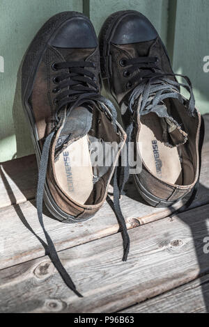 Vue rapprochée de classic noir usé chaussures Converse All Star appuyé contre mur Banque D'Images