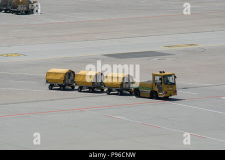 Yellow Freight avec chariots à bagages chargés sur le tarmac de la piste de l'aéroport de Stuttgart Banque D'Images