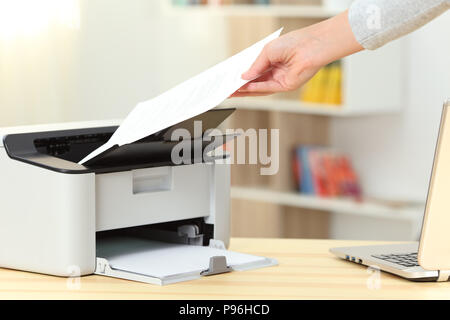 Gros plan d'une femme part de la capture d'un document à partir d'une imprimante sur un bureau à la maison Banque D'Images