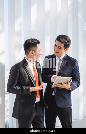 Deux hommes vietnamiens coworkers talking and smiling Banque D'Images
