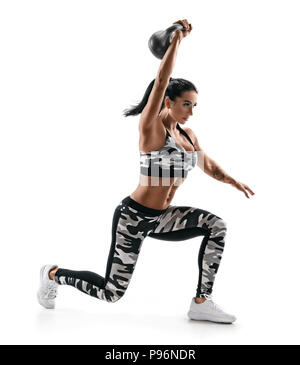 Femme forte muscles formation des mains et les jambes à l'aide d'une kettlebell. Photo de belle femme mode dans le sportswear isolé sur fond blanc. Banque D'Images