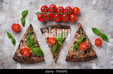 Des morceaux de pizza noir avec tomates et basilic Banque D'Images